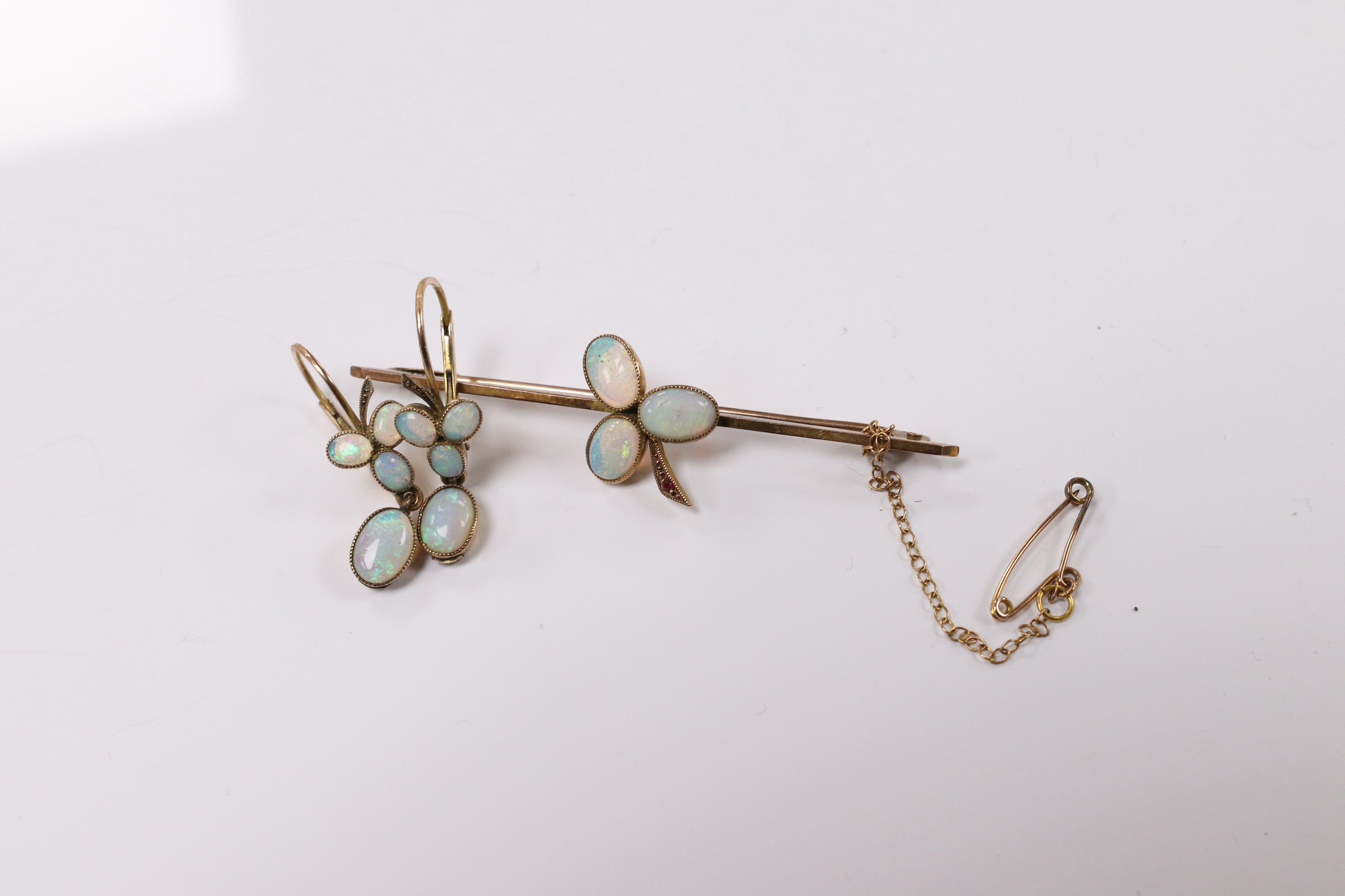 A 9ct and three stone white opal and single stone ruby set bar brooch, 58mm, together with a pair of yellow metal and opal cluster set earrings. Condition - fair